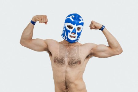 Téléchargez les photos : Portrait d'un homme torse nu en masque de lutte flexion des muscles sur fond gris - en image libre de droit