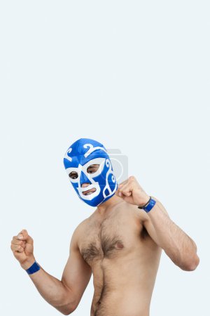 Photo for Portrait of a young male wrestler celebrating victory against gray background - Royalty Free Image
