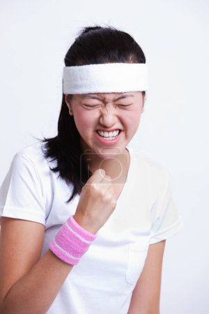 Photo for Young female tennis player celebrating success against white background - Royalty Free Image