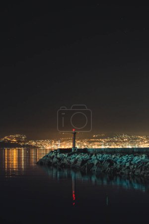 Téléchargez les photos : "Phare pendant la nuit avec l'horizon de la ville pendant que le fond" - en image libre de droit