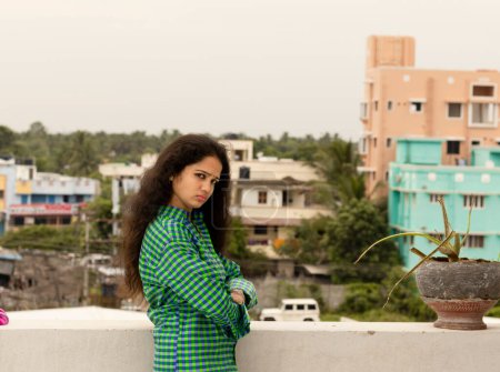 Foto de Una joven hindú mujer india de pie en un ambiente abierto por encima del techo de la casa y felizmente fotografiado hermoso - Imagen libre de derechos