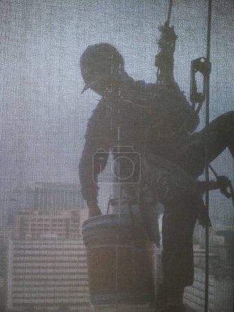 Téléchargez les photos : Images de silhouette de l'homme nettoyant le bâtiment de bureaux de fenêtres - en image libre de droit