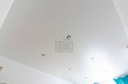 Téléchargez les photos : Fragment de l'intérieur de la pièce plafond tendu mat blanc avec une série de projecteurs - en image libre de droit