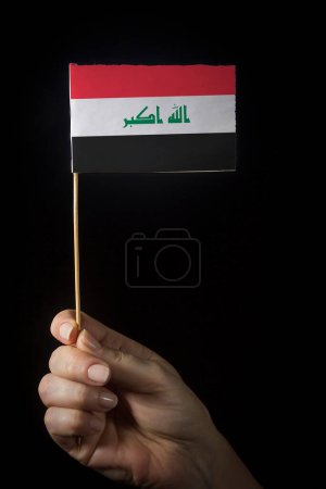 Foto de Mano con bandera de Irak sobre fondo oscuro - Imagen libre de derechos