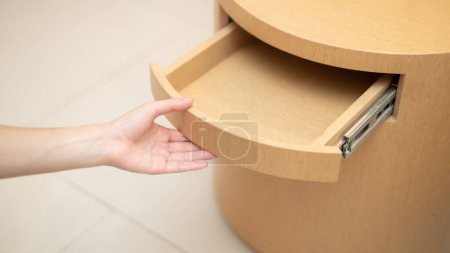 Photo for Woman hand opening a drawer in the wooden table. - Royalty Free Image