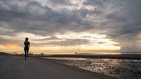 Photo for Woman jogging on beach in the morning. - Royalty Free Image