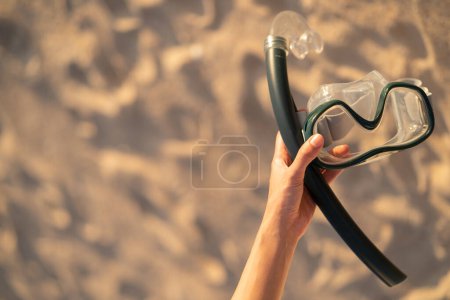 Téléchargez les photos : Main avec équipement pour masque de plongée en apnée à la plage. - en image libre de droit
