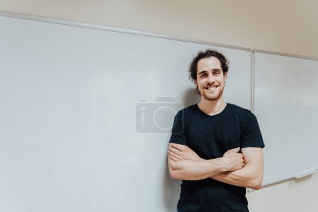 Photo for Young male teacher in front of a board smiling to camera - Royalty Free Image