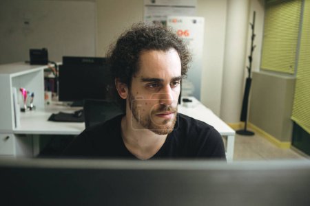 Foto de Joven hombre trabajando delante de la computadora, vista desde detrás de la computadora - Imagen libre de derechos