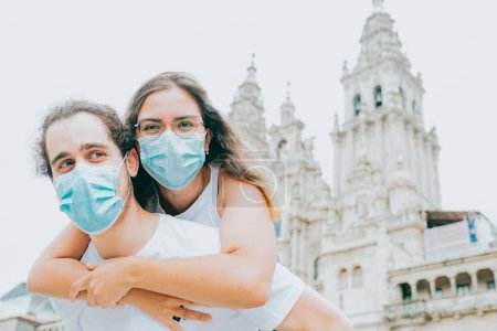 Photo for Young couple smiling with the masks on while visiting and old part of the city - Royalty Free Image