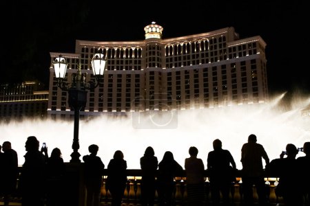 Foto de Escena nocturna con siluetas de gente admirando el espectáculo de las fuentes de Bellagio en Las Vegas - Imagen libre de derechos