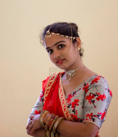Téléchargez les photos : Une belle jeune fille hindoue aux ornements dorés et au rouge à lèvres rouge sur ses jolies lèvres douces - en image libre de droit