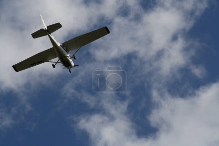 Foto de Un avión volando a través de un cielo azul nublado - Imagen libre de derechos