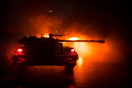 Foto de Concepto de guerra. Siluetas militares que luchan escena en el fondo del cielo niebla de guerra, Guerra Mundial tanques alemanes siluetas debajo del horizonte nublado Por la noche. Escena de ataque. Vehículos blindados. Batalla de tanques - Imagen libre de derechos