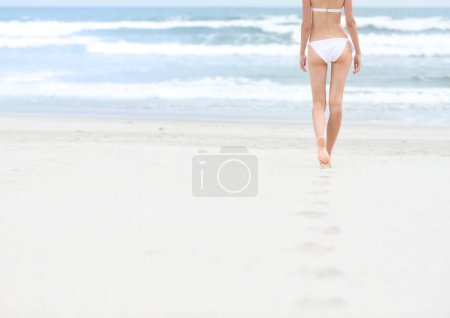 Photo for Slim girl in white swimsuit walking to ocean. - Royalty Free Image