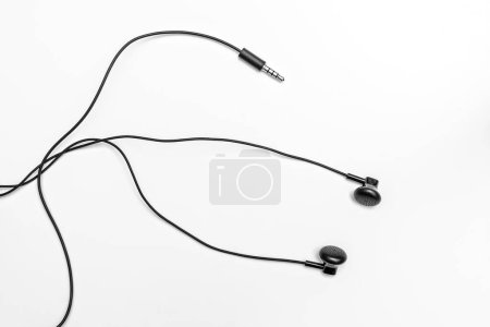 Photo for Small black headphones on a light background with tangled long wires - Royalty Free Image