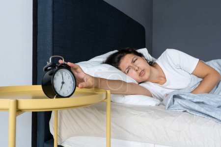 Foto de La chica apaga el molesto despertador para seguir durmiendo - Imagen libre de derechos