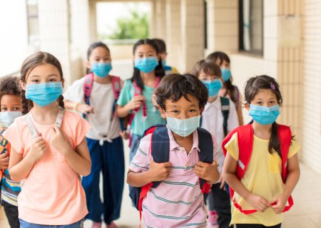 Téléchargez les photos : Enfants portant un masque médical pour le visage de retour à l'école après la quarantaine covid-19 - en image libre de droit