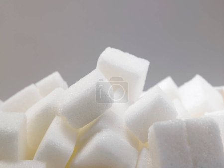 Téléchargez les photos : Vue rapprochée des cubes de sucre sur fond gris - en image libre de droit
