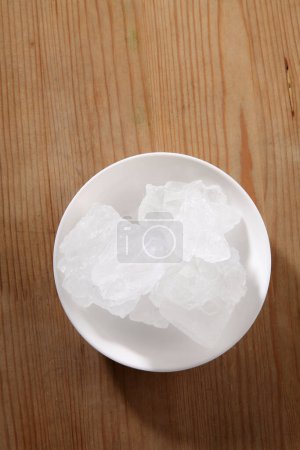 Foto de Azúcar de roca en tazón sobre fondo de madera - Imagen libre de derechos