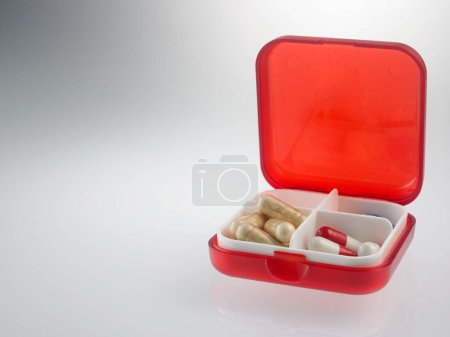 Téléchargez les photos : Vue rapprochée de la boîte à pilules rouge sur fond gris - en image libre de droit