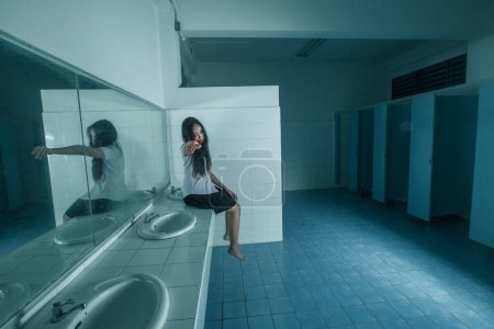 Photo for Ghost university girl sitting in restroom - Royalty Free Image