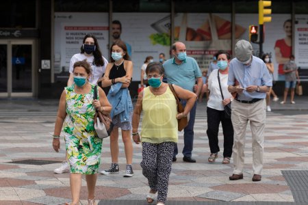 Photo for Zaragoza, Spain - August 18, 2020: People walking in a crosswalk with face masks - Royalty Free Image