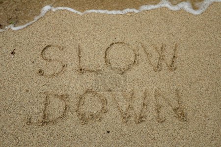 Téléchargez les photos : "ralentir, concept de pleine conscience écrit sur le sable" - en image libre de droit