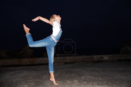 Photo for Barefoot teenage girl dancing ballet on an empty pier at night - Royalty Free Image