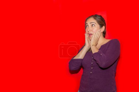 Téléchargez les photos : Femme réfléchie en chemise violette sur fond rouge avec espace de copie - en image libre de droit