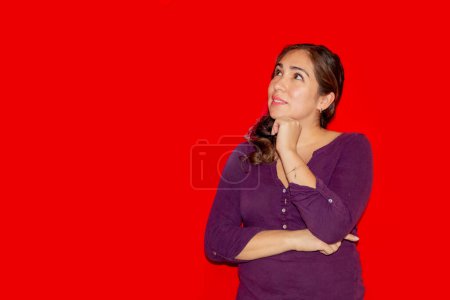 Foto de Mujer reflexiva en camisa púrpura sobre fondo rojo con espacio para copiar - Imagen libre de derechos