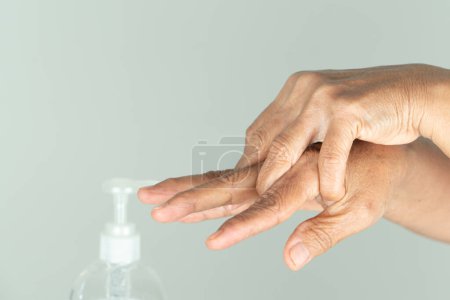Téléchargez les photos : Femme âgée propre main par gel d'alcool ou savon anti-bactéries - en image libre de droit