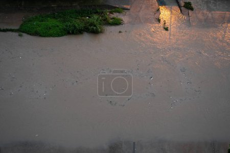 Foto de Canal del río en una gran ciudad. Las aguas residuales después de la lluvia llevan basura a lo largo del río. - Imagen libre de derechos
