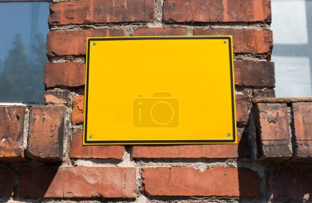 Téléchargez les photos : Panneau vierge en métal jaune sur un vieux mur de briques - en image libre de droit