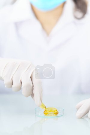 Foto de Científico sosteniendo cápsula Omega 3 en bata de laboratorio - Imagen libre de derechos