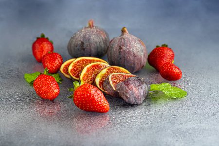 Téléchargez les photos : Figues fraîches avec des fraises sur un fond sombre. Plat d'automne. Cuisine d'automne décontractée. Récolte d'automne - en image libre de droit