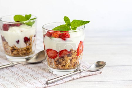 Photo for Homemade granola with slices of strawberries in transparent glasses on a light background. Vegetarian dish. Healthy breakfast - Royalty Free Image