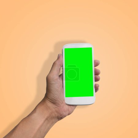 Foto de "Mano sosteniendo el teléfono inteligente con pantalla verde aislada
 " - Imagen libre de derechos