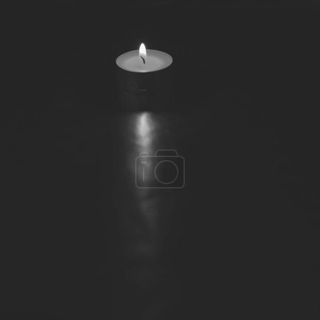 Foto de Pequeña vela encendida sobre fondo oscuro y plateado - Imagen libre de derechos