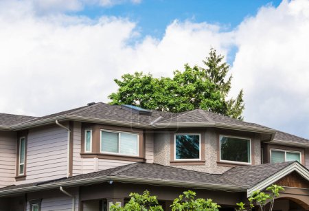 Téléchargez les photos : Le sommet de la maison avec de belles fenêtres sur fond de ciel nuageux
. - en image libre de droit
