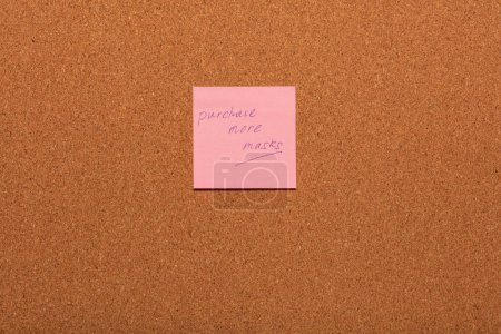 Téléchargez les photos : Rappel Acheter plus de masques manuscrits sur un autocollant rose sur un tableau d'affichage en liège. - en image libre de droit