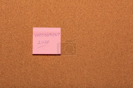 Téléchargez les photos : Vaccination 2020? manuscrit sur un autocollant rose sur un tableau d'affichage en liège. - en image libre de droit