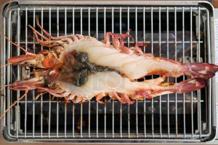 Téléchargez les photos : Crevette tigrée crue fraîche coupée en deux sur grille-barbecue au gaz. - en image libre de droit