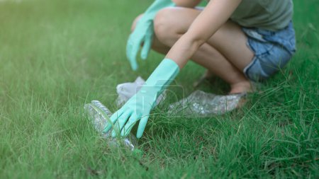 Foto de Woman hand keeping plastic waste into black bag at park - Imagen libre de derechos