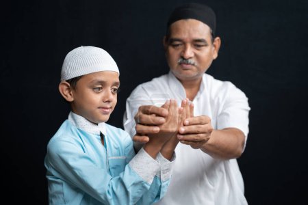 Photo for Muslim Father teaching his son how to do Salah or payer in a Islamic way - Royalty Free Image