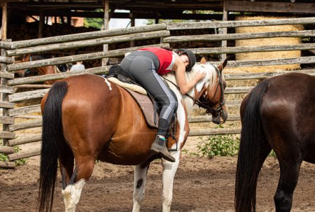 Foto de Mujer acostada en el caballo y abrazándose después de montar a caballo - Imagen libre de derechos