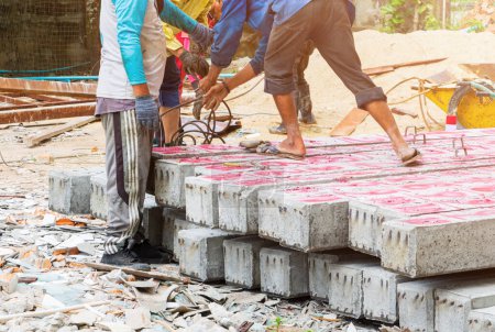 Téléchargez les photos : Travailleur déplacer pieux de béton piliers sur le sol - en image libre de droit