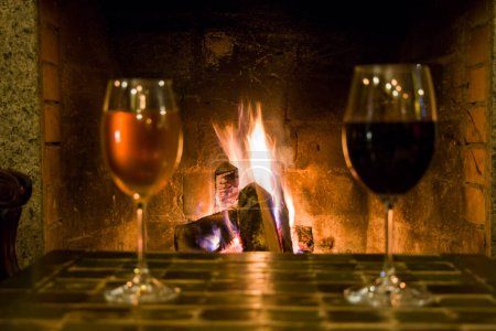 Photo for Full wine glasses on the table and fireplace on background - Royalty Free Image