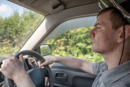 Téléchargez les photos : Le visage d'un paysan, un conducteur qui conduit une voiture le long d'un champ agricole - en image libre de droit