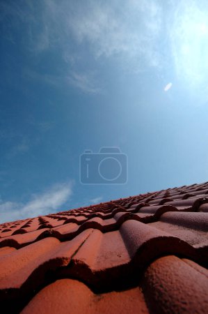 Téléchargez les photos : "Tuiles rouges sur un toit de maison sous le ciel bleu" - en image libre de droit
